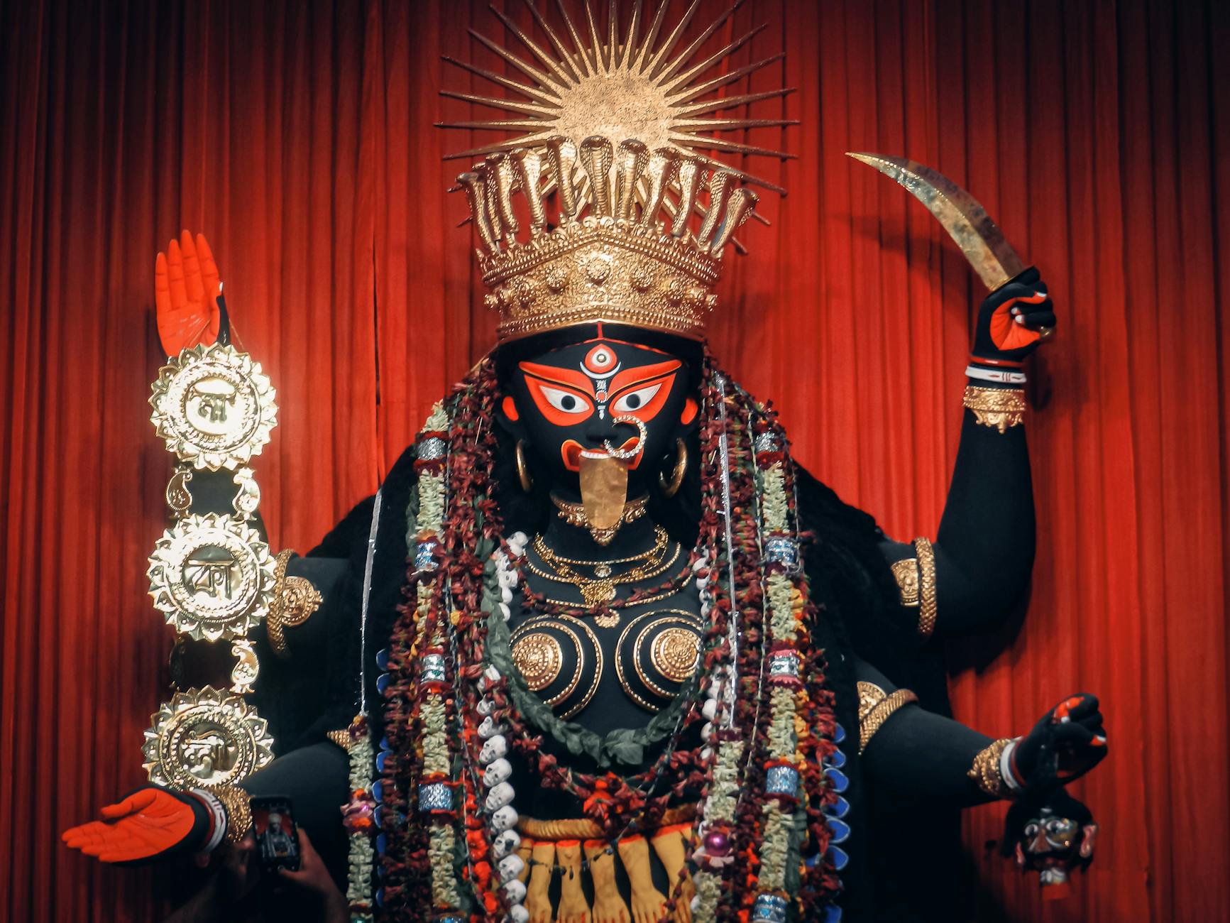 figure of goddess kali against red curtain