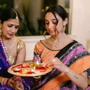 a woman lighting a candle of a puja thali