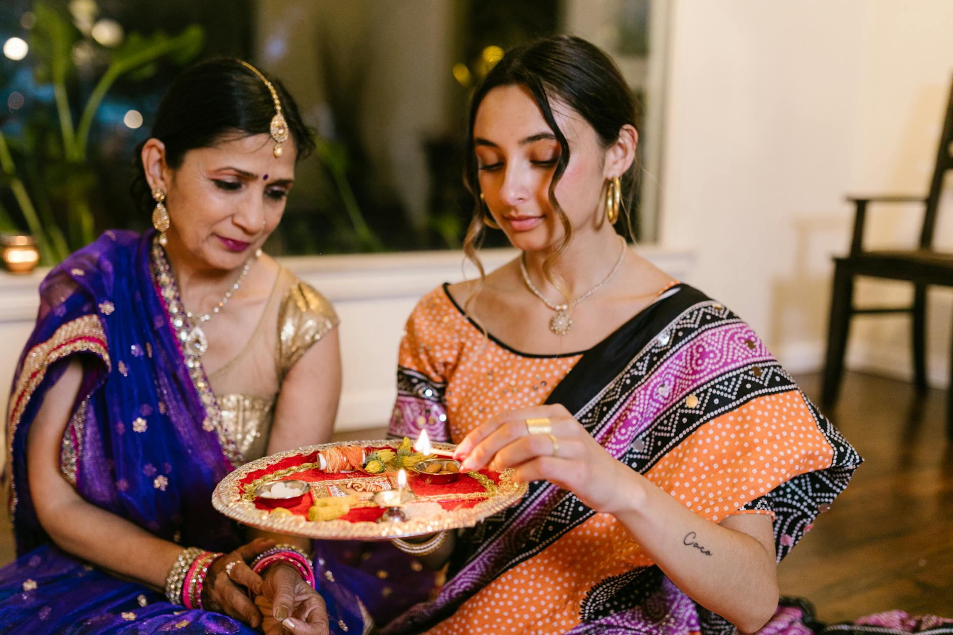 a woman lighting a candle of a puja thali