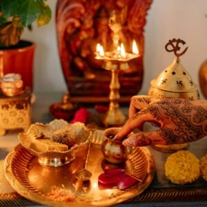 hand of a person with mehandi touching a gold cup traditional ritual decorations on table