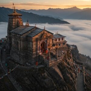 A majestic aerial view of the ancient Aadi Himani Chamunda temple perched dramatically on a Himalayan cliff edge at 11,000 feet, surrounded by misty mountain peaks at sunrise. The temple architecture features intricate Pahari-style carved details glowing in golden morning light. In the foreground, a winding mountain path adorned with prayer flags leads to the temple, where devotees in traditional Himachali attire make their ascent. The scene is rendered in a blend of photorealistic and mystical styles, with soft ethereal fog wrapping around the mountains. The temple courtyard shows the main shrine with traditional brass bells and diyas. Goddess Chamunda's divine presence is suggested through a subtle, warm golden aura emanating from the temple sanctum. The color palette combines deep earthy browns of the mountains, misty blues of the dawn sky, and touches of saffron and gold in the temple details. The atmosphere captures both the spiritual significance and the physical challenge of the pilgrimage, with dramatic lighting and atmospheric perspective creating depth and scale.